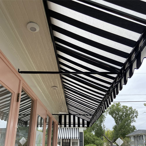 Black and White striped retractable awning over pink peach framed glass doors